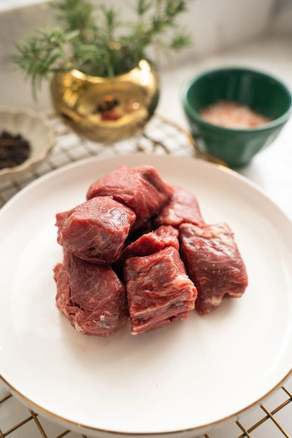 Raw beef cubes on a white plate